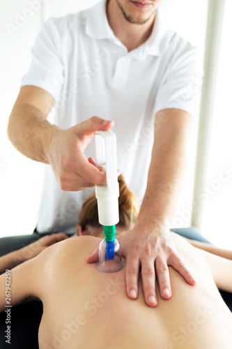 Physiotherapist applying cupping treatment to the patient in a physiotherapy room.