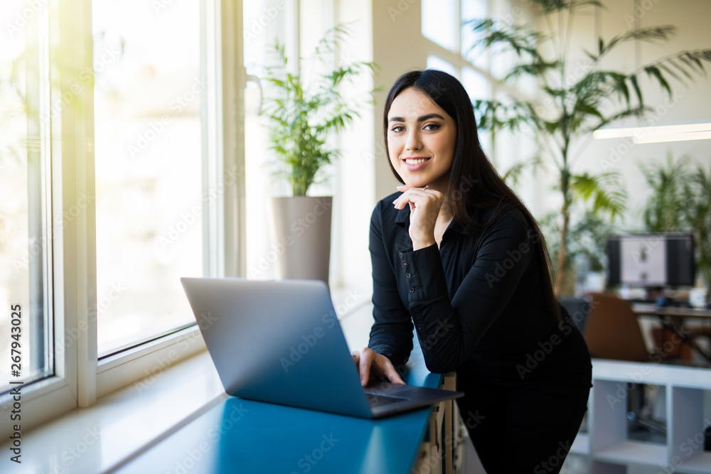 Beautiful businesswoman is using a laptop and smiling while working in office Beautiful businesswoman is using a laptop and smiling while working in office