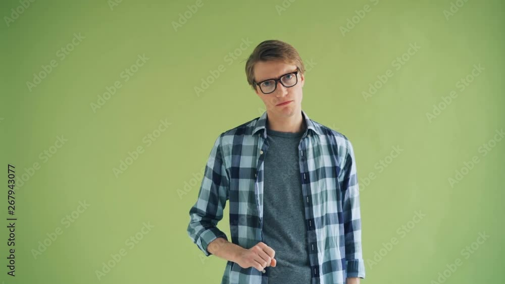 Portrait of serious guy hipster shaking head and waving finger showing no gesture standing on green background. Youth, human reactions and people concept. Portrait of serious guy hipster shaking head and waving finger showing no gesture standing on green background. Youth, human reactions and people concept.