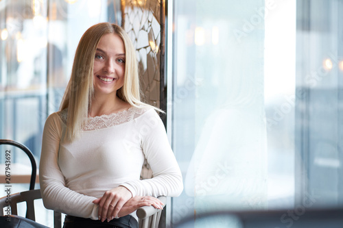 Portrait of young blonde smiling girl sitting near window Free Download Portrait of young blonde smiling girl sitting near window - GFXLoad