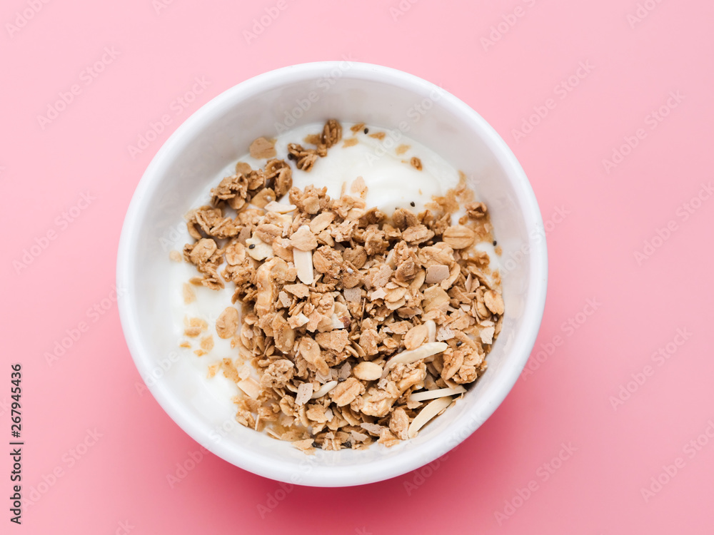Whole grains on yogurt in white bowl, pink background. Whole grains on yogurt in white bowl, pink background.
