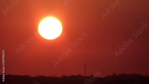 Tropical sunset with clouds. Beautiful sunset image of the golden hour. A dark orange sky with clouds and the shining sun going down.