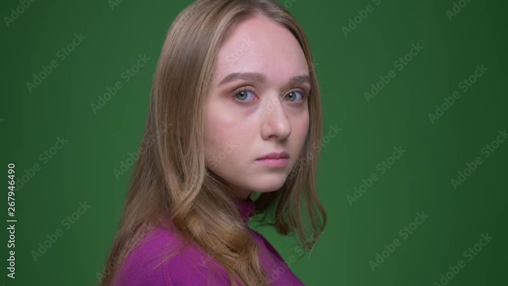 Portrait of beautiful ginger student turns to camera watching calmly into it on green chroma background. Portrait of beautiful ginger student turns to camera watching calmly into it on green chroma background.