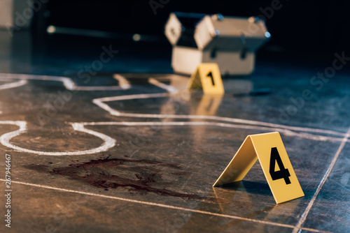 Foto chalk outline, blood stain, investigation kit and evidence markers at crime scen