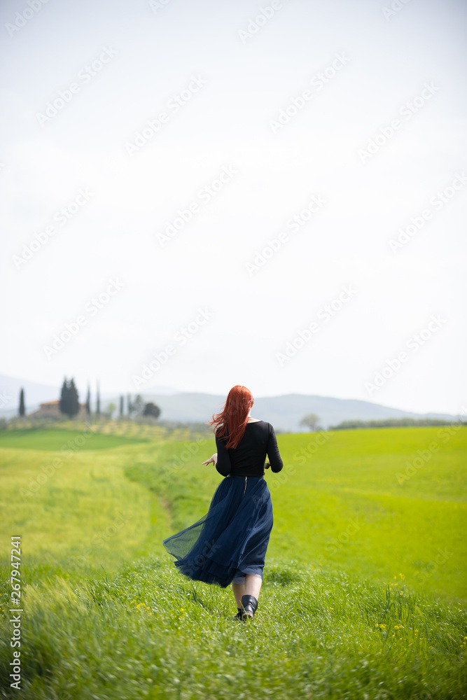 A woman in a long dress standing on a bright green meadow