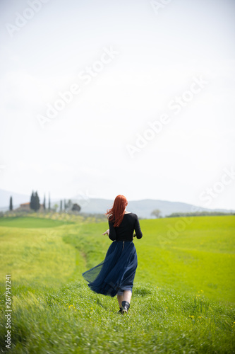 A woman in a long dress standing on a bright green meadow