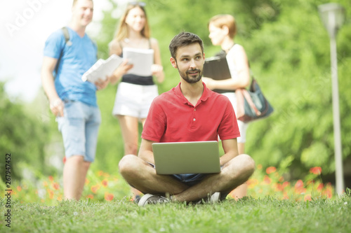 Young student with laptop outdoors in park