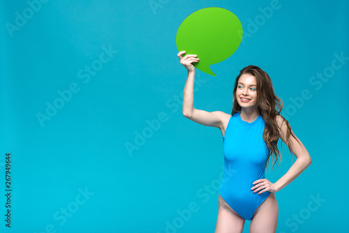 charming girl in swimsuit holding speech bubble isolated on blue