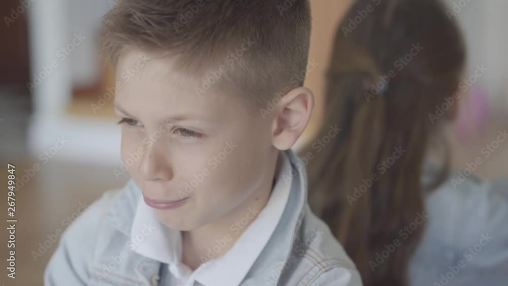 Portrait little caucasian brother and sister twins sit offended and angry with their backs to each other with a displeased faces Portrait little caucasian brother and sister twins sit offended and angry with their backs to each other with a displeased faces