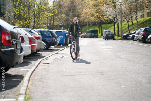 Young woman on a Bicycle, riding around the city near the car