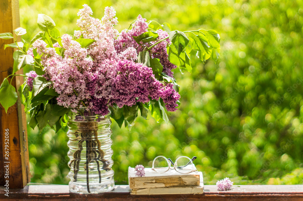 Book, glasses, cup of tea and lilac on a wooden window. Fragrant tea in the garden. Romantic concept. Vintage style Book, glasses, cup of tea and lilac on a wooden window. Fragrant tea in the garden. Romantic concept. Vintage style