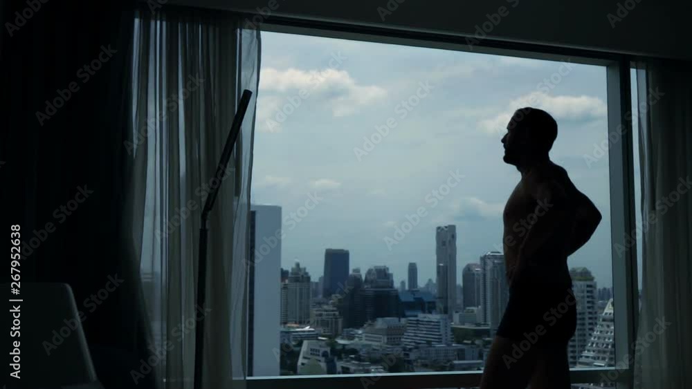 Man admire city view standing by window at home, slow motion Man admire city view standing by window at home, slow motion