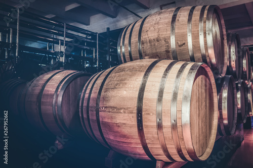 Wooden barrels with cognac in dark cellar. Ancient traditions of cognac production