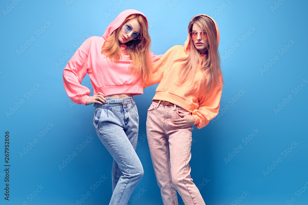 Fashion. Two hipster Girl in trendy colorful neon Outfit Fooling Around in  Studio. Young Tomboy Friends Having Fun relax. Shapely Woman with  fashionable makeup. Funny art neon style Stock Photo