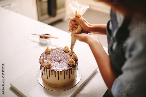 Fotografia Chef decorating cake with cream