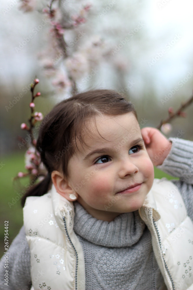 portrait of a beautiful cheerful little girl on a background of a blossoming tree portrait of a beautiful cheerful little girl on a background of a blossoming tree