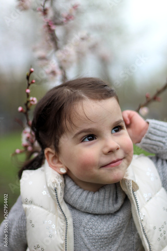 portrait of a beautiful cheerful little girl on a background of a blossoming tree