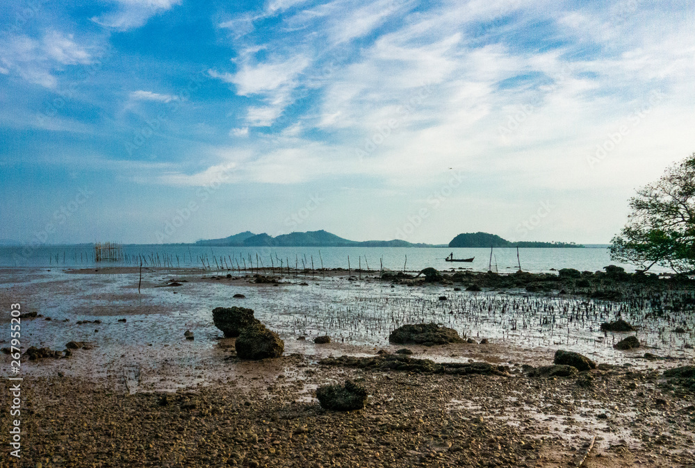 Sea shore on a low tide day overlooking to small fisherman boat in the open sea.