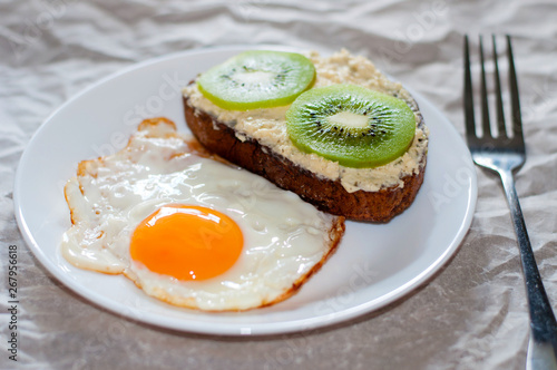 Delicious and healthy breakfast. Fried eggs and kiwi sandwich on white plate