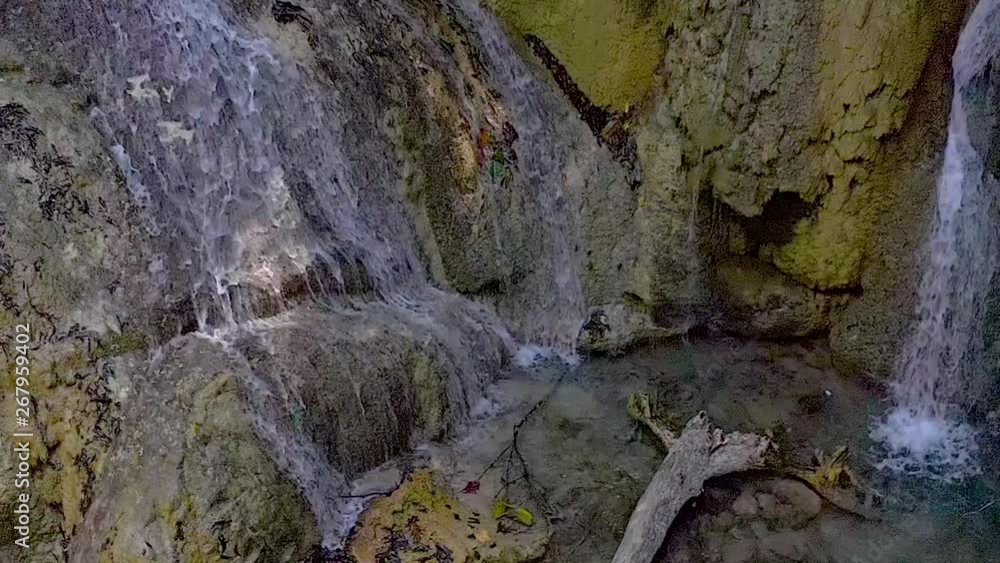 Moving in towards colourful, serene, splashing waterfalls at the base of tropical, jungle foliage. Stones & branches seen through clear, clean water pool at the base of the waterfall. Moving in towards colourful, serene, splashing waterfalls at the base of tropical, jungle foliage. Stones & branches seen through clear, clean water pool at the base of the waterfall.
