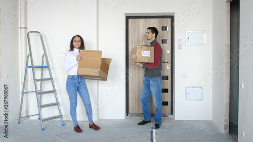 A young attractive couple moving into a new home. A couple is standing on the doorstep