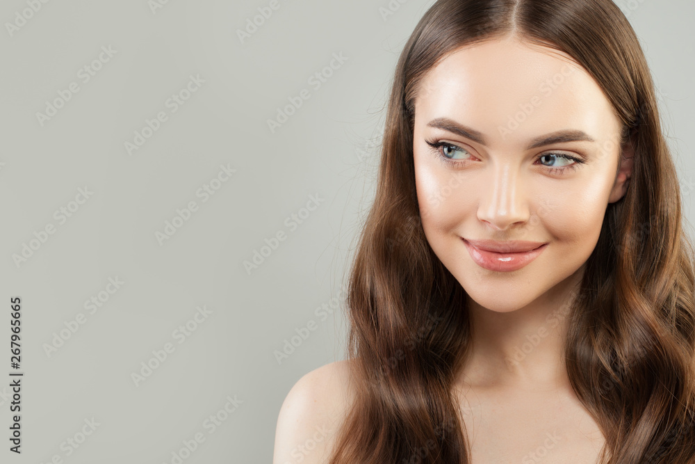 Portrait of cheerful woman with clear skin and healthy curly hair on gray background. Beautiful face close up. Skincare and facial treatment concept Portrait of cheerful woman with clear skin and healthy curly hair on gray background. Beautiful face close up. Skincare and facial treatment concept