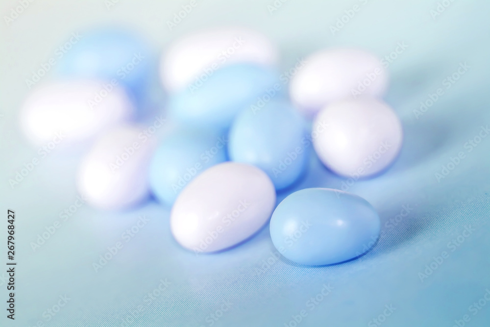 Assorted fullcolor blue and white candy dragees on blue background.