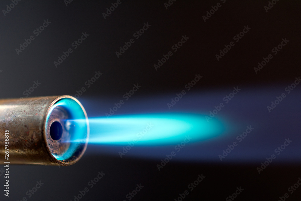 Industrial gas burner with blue flame, close up shot in the dark