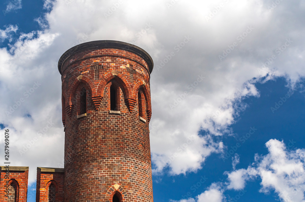 Round brick tower and part of the wall against the blue sky with clouds Round brick tower and part of the wall against the blue sky with clouds