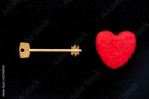 Golden key with red plush heart on black background © Kiryl Lis