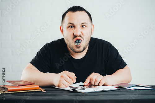 angry man sitting at a table full mouth of finger batteries, the concept of excess of harmful substances and objects photo