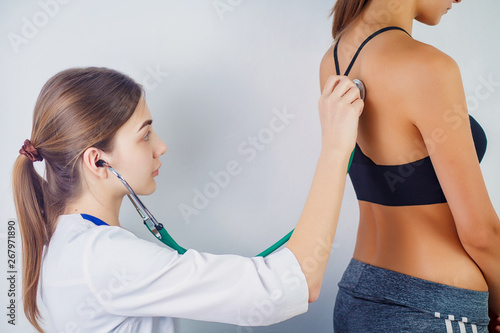 Doctor checking breathing with stethoscop of a female patient. Doctor sitting near the patient and listening to the noise in his organism using a stethoscope. Close-up.