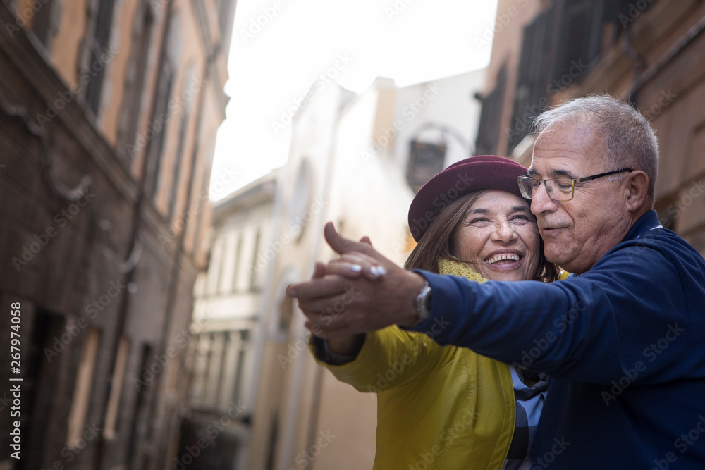 coppia di anziani balla felice in mezzo a una strada - obrazy, fototapety, plakaty 