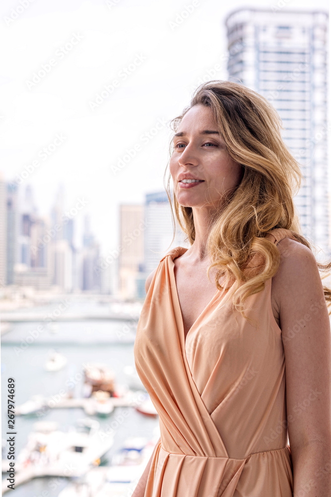 Woman in Dubai Marina, United Arab Emirates. Attractive lady wearing a long dress admiring Marina daylight views Woman in Dubai Marina, United Arab Emirates. Attractive lady wearing a long dress admiring Marina daylight views