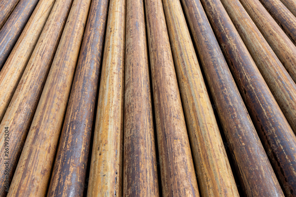 Rusty grunge pipes horizontal background. Orange corrosion rust on steel metal factory industrial pattern. Rough texture brown parallel stack close up Rusty grunge pipes horizontal background. Orange corrosion rust on steel metal factory industrial pattern. Rough texture brown parallel stack close up