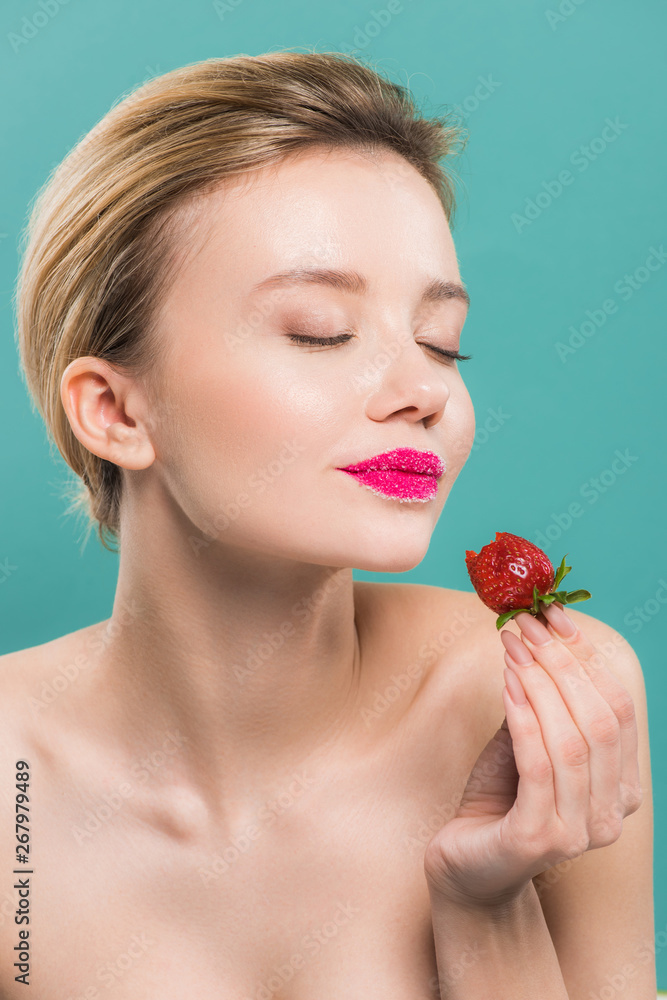 attractive girl with sugar on lips holding strawberry isolated on blue