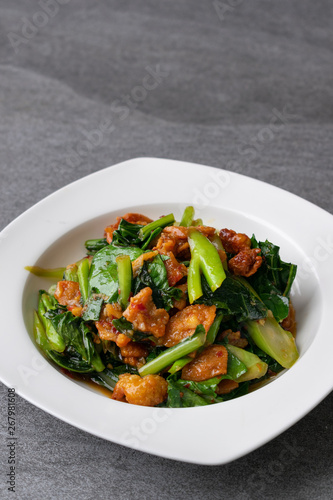 Fried Chinese kale with crispy skin chicken in oyster sauce and chilli in the white dish.