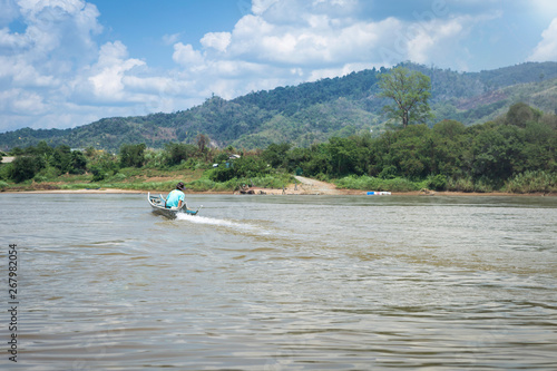 Man on wooden fishing boat on Maekhong river heading to Lao border, outdoor day light, Tropical nature, river in Thailand