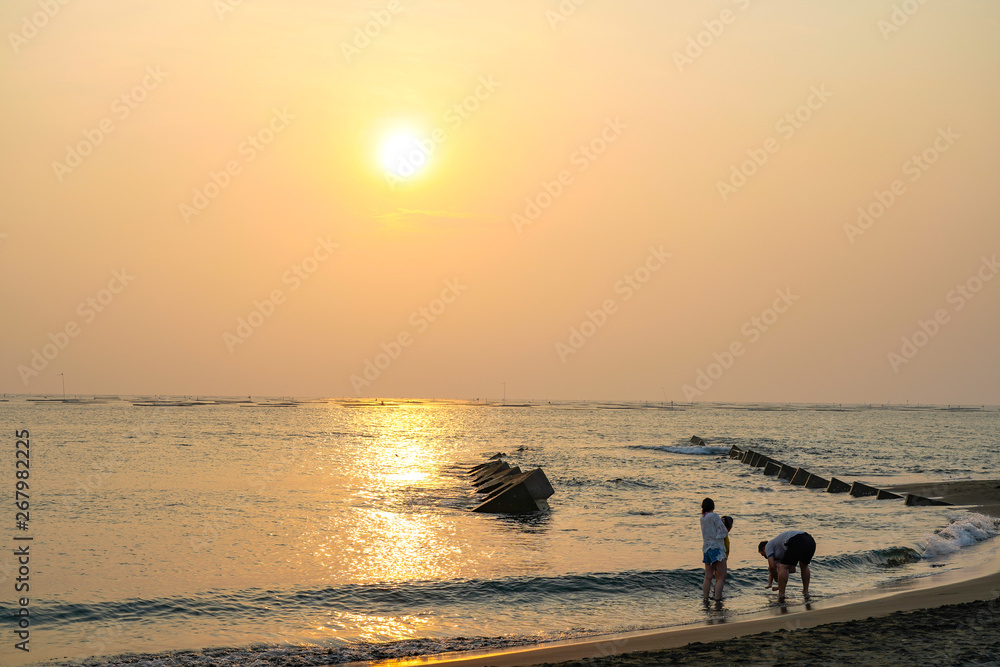 Golden Coast. The largest beach within Tainan, Taiwan. View from the beach with a yellow glowing sun setting in the horizon with a family enjoy fun here. 