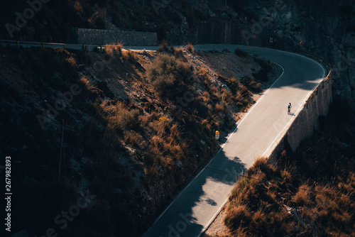 Obraz na plátně Biker silhouette on the road bicycle ride uphill