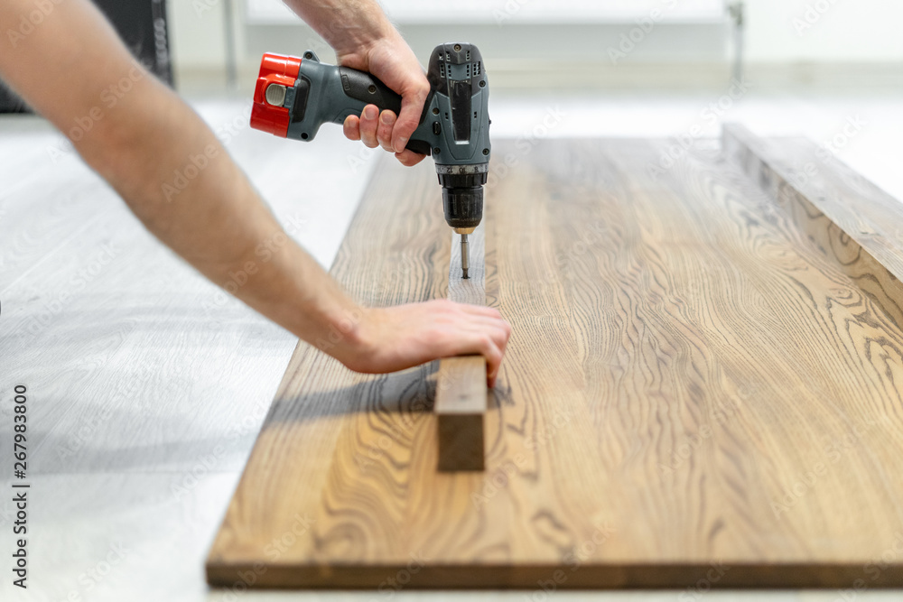 Man using screwdriver fasten plank on wooden table top