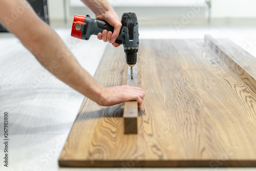 Принти на полотні Man using screwdriver fasten plank on wooden table top