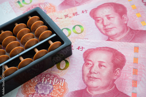 Chinese abacus on Chairman Mao portrait 100 Chinese paper currency Yuan renminbi banknotes background. China or economy of Asia growth, financial business, US trade war concept photo