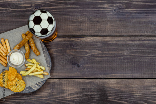 Diverse snacks with beer on dark wooden background. Top view, Empty space for text