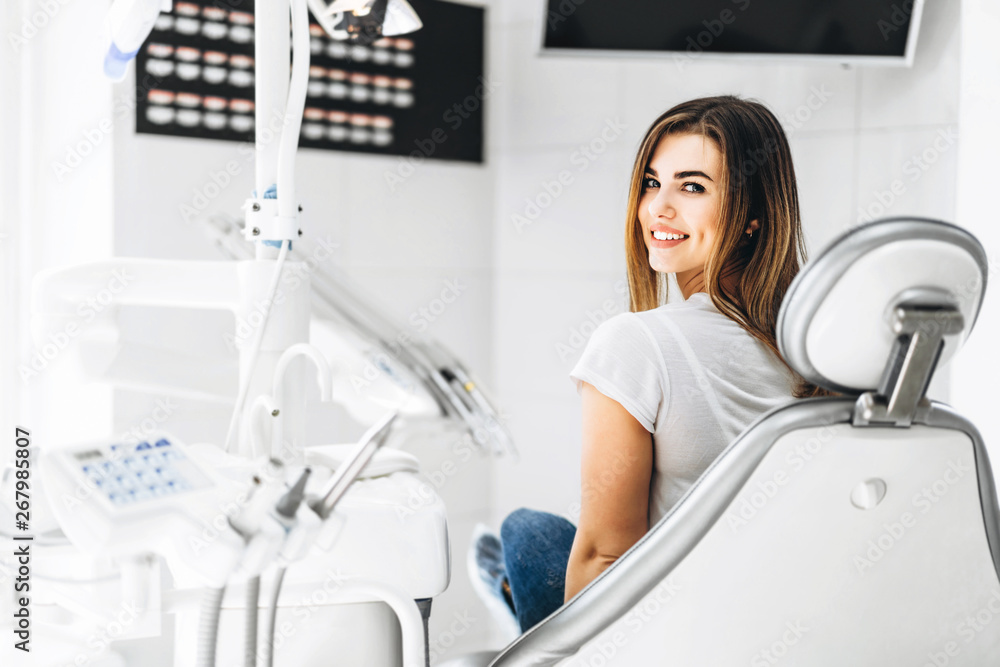 Pretty happy and smiling dental patient sitting in the dental chair at the dental office. Pretty happy and smiling dental patient sitting in the dental chair at the dental office.