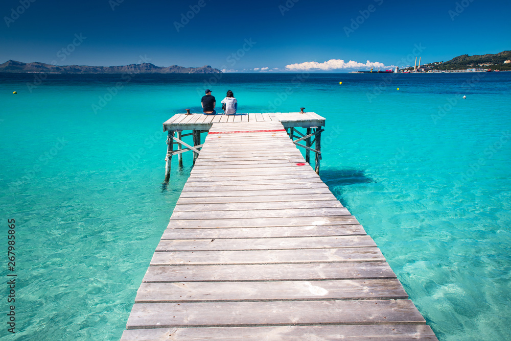 Tourist sitting together on the pier in tropical sea. Spain.