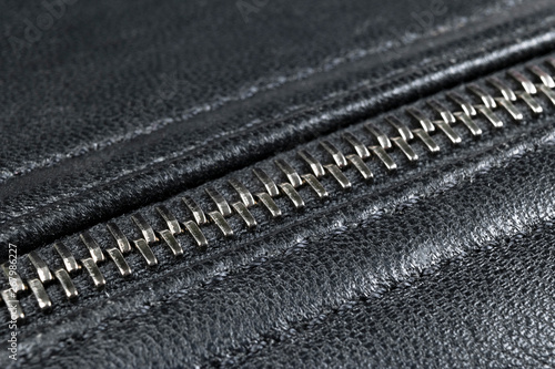 Macro shot of zipper on black leather texture background with stitching. Horizontal background from a close-up of black leather material