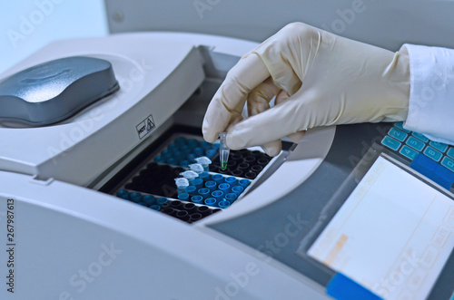 Scientist holding PCR tube put into PCR machine