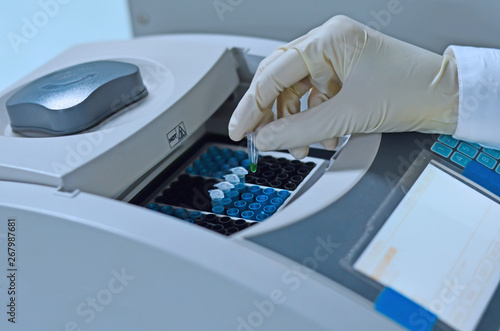 Scientist holding PCR tube put into PCR machine photo
