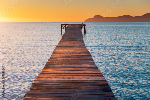 Pier in orange sunrise colors. Playa de Muro